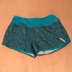 NWOT Reebok athletic dolphin hem shorts with built-in briefs. Mostly teal. XS.